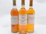 trois bouteilles de vin posées les unes à côté des autres sur une surface blanche