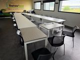 des tables et des chaises dans une salle de réunion, avec une grande fenêtre en arrière-plan