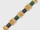 a close up of a gold and green bracelet on a white surface