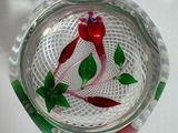 un bol en verre orné d'une fleur rouge et de feuilles vertes