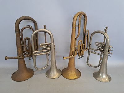 three brass trumpets sitting next to each other on a white surface