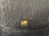 a close up of a black purse with a gold h on it