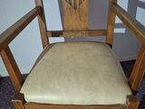 a wooden chair with a tan cushion on it