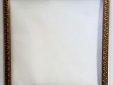 un cadre doré accroché à un mur sur fond blanc