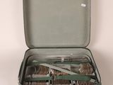 a green suitcase with silverware in it on a white surface