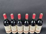 six bottles of red wine lined up in a row