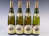 four bottles of wine are lined up on a white surface