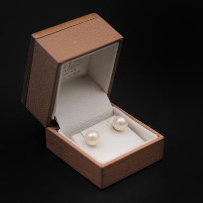 une boîte ouverte contenant une paire de perles, sur fond noir