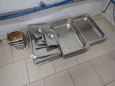 Plusieurs plateaux de nourriture sont alignés par terre dans une cuisine