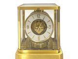 une horloge en or posée sur une surface blanche