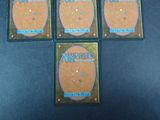 four magic the gathering trading cards are sitting on a table