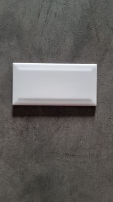 a close up of a white rectangular tile on a gray surface
