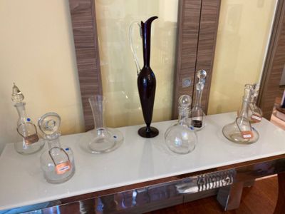 a black vase sitting on top of a table next to other glass vases