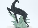 statue d'une chèvre noire posée sur un socle blanc, sur fond blanc