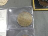 two gold coins sitting on a table next to a picture of a woman
