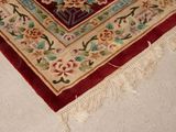 a red rug with a floral design on it on the floor