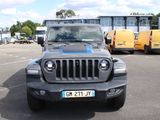 une jeep grise garée sur un parking, avec d'autres véhicules en arrière-plan