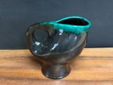 black and green ceramic vase on wooden table with black background