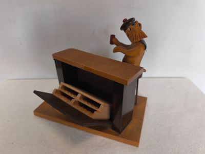 une statue en bois représentant un homme assis à un bureau devant un ordinateur