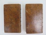 pair of old leather bound books sitting on a white surface