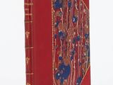 un vieux livre à la couverture rouge, rehaussée de dorures, sur un fond blanc