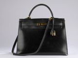 a black leather handbag with a gold lock on the handle