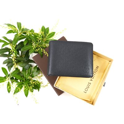 a black leather wallet sitting on top of a stack of books