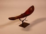 a wooden bird on a stand on a white surface