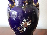 a purple vase sitting on a table with a white wall in the background
