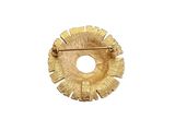 a gold brooch on a white surface with a white background