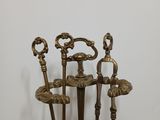 four antique brass candlesticks with ornate handles on a wooden stand