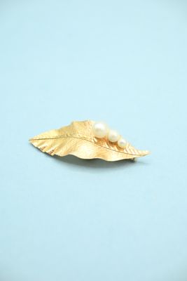 a gold leaf with a pearl on it on a blue surface