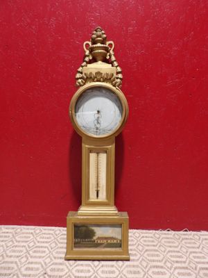 une horloge dorée posée sur une table devant un mur rouge