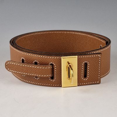 ceinture en cuir marron avec une boucle dorée sur un fond blanc