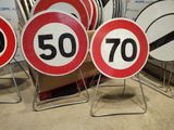 several red and white speed limit signs sitting next to each other
