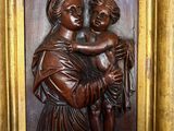 wooden relief of a woman holding a child in a gold frame