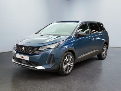 La voiture bleue est garée dans une grande pièce au sol noir.