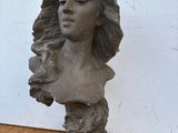 sculpture représentant la tête d'une femme aux cheveux longs, posée sur une table en bois