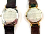 two watches sitting next to each other on a white surface