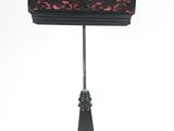 une photo d'une lampe de table noire et rouge posée sur un pied