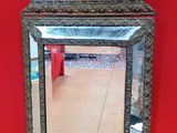 un miroir accroché à un mur rouge, avec une chaise rouge en arrière-plan