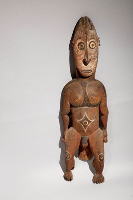 an image of a wooden statue of a man sitting on a white surface
