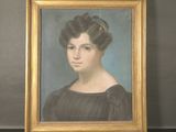 portrait d'une femme en robe noire, dans un cadre doré, posé sur une table noire