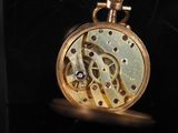 a close up of a pocket watch on a black surface