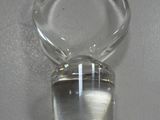 a clear glass bottle with a small amount of water inside of it