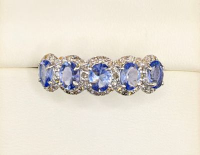 a close up of a blue and white diamond ring on a white surface