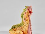 figurine représentant un dragon jaune et vert assis sur une surface blanche
