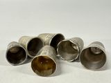 four silver metal cups with a brown substance in them on a white surface