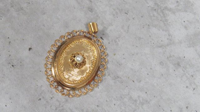 Pendentif ovale à décor centré d’une petite perle en or 18 carats...