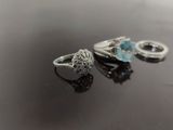 pair of silver rings with blue topaz stones on a black surface